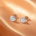 Diamond stud earrings on champagne silk background